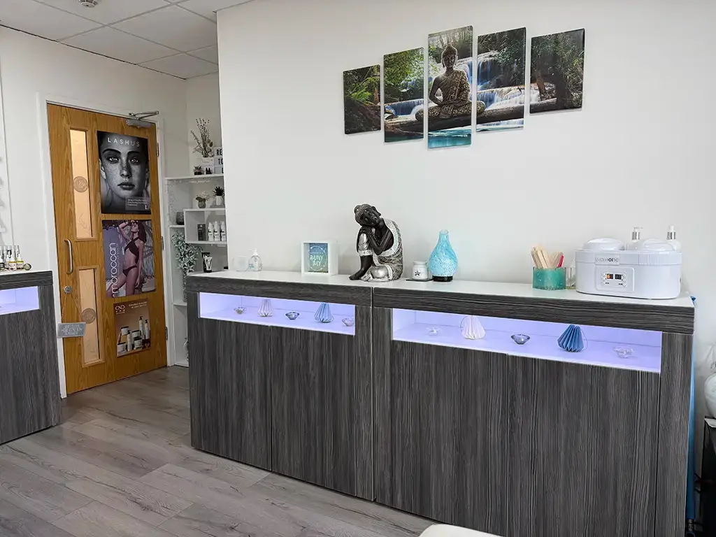 A modern spa room in Ipswich with wooden counters, decorative shells, a Buddha statue, calming artwork, and neat spa equipment—perfect for a beauty therapist creating a peaceful and serene atmosphere.